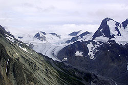 A glacier carves around peaks and valleys.