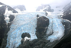 Photo courtesy of Debra Austin. Two blue glaciers flow up and over a rock.