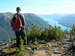 Photo courtesy of Bill and Anita Miller. A man stands on a hill high above a long aqua green lake and valley.