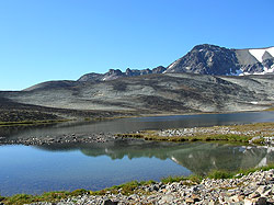 Photo courtesy of Bill and Anita Miller. Barren, rocky hills surround a high, clear lake.