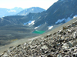 Photo courtesy of Bill and Anita Miller. Rocky sidehill overlooks a tiny, blue green lake.