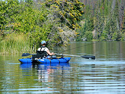 A woman flyfishes among the reeds in a personal pontoon boat.